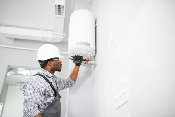 African american worker set up gas heating boiler at home.